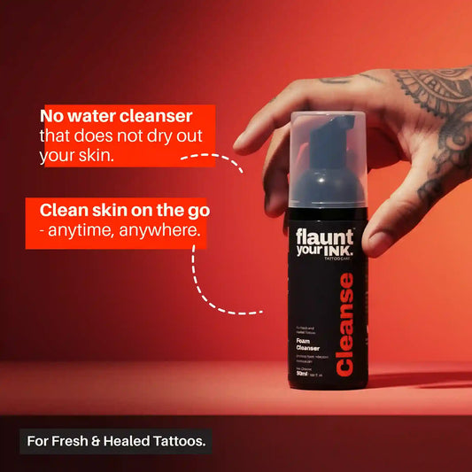 Hand holding a bottle of ' flaunt your INK' Cleanse foam cleanser against a red background